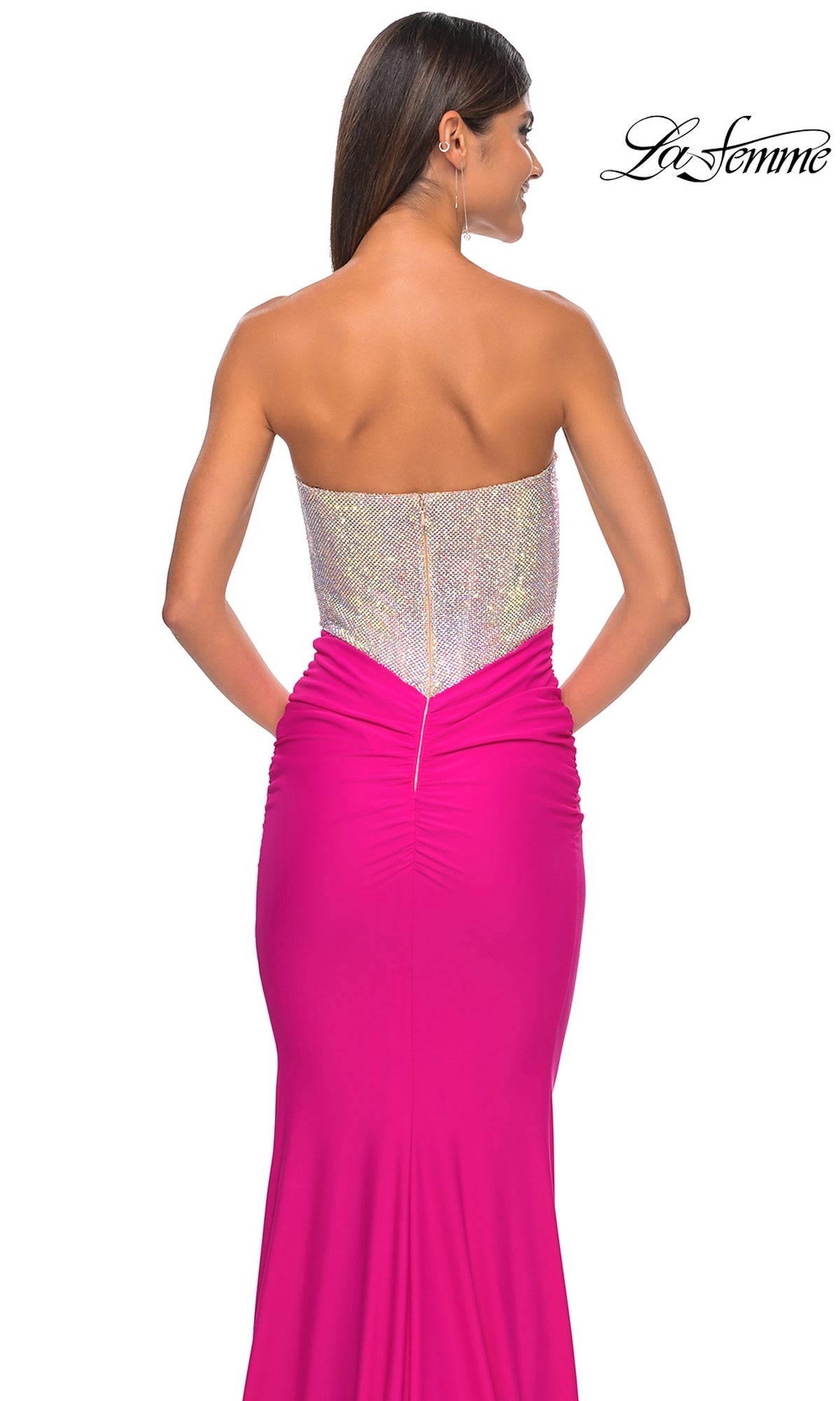 A woman is seen from the back against a white background wearing the Strapless Hot Pink Long Prom Dress La Femme 32440, featuring a form-fitting floor-length skirt and sparkling silver bodice.